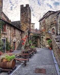 there are many benches in the middle of this street with stone buildings on both sides