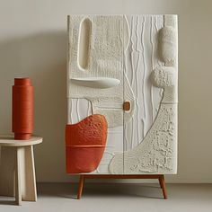 an orange chair sitting in front of a white door with trees on it and a spool of thread next to it