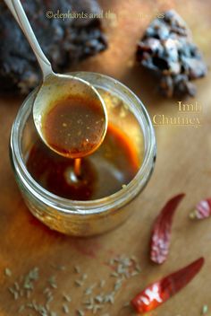 a spoon full of honey sitting on top of a wooden table next to some spices