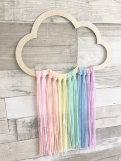 an image of a rainbow cloud with fringes hanging from it's side on a wooden wall