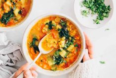 two bowls of vegetable soup with a spoon in one and another bowl on the other