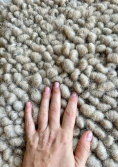 a person's hand on top of a rug that looks like it is made out of wool