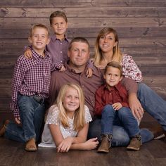 a family posing for a photo in front of a wooden wall