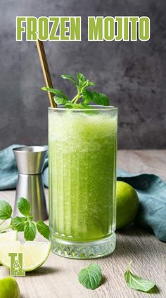 a green smoothie in a glass with mint and lime on the side next to it