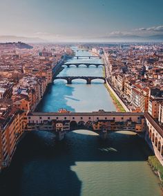 an aerial view of a river running through a city with bridges and buildings in the background