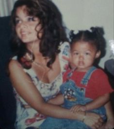 an old photo of a woman holding a child in her lap and smiling at the camera