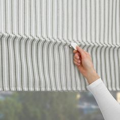 a person is pulling up the blinds with their hand