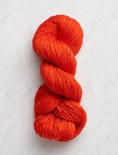 two skeins of orange yarn on a white surface