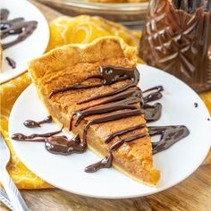 a piece of pie with chocolate drizzled on it sitting on a white plate