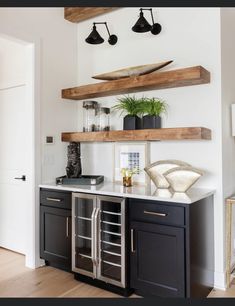 a kitchen with black cabinets and wooden shelves above the counter top, along with potted plants