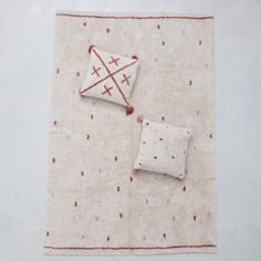 two pillows and a pillow on a white surface with red dots in the middle, placed next to each other