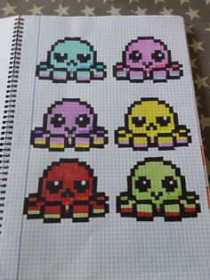 an open notebook with pixel art on it and skulls in different colors sitting next to each other