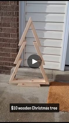 a wooden christmas tree sitting on top of a door mat in front of a house