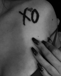 a woman with red nail polish holding her hand up to her chest and the word xo tattooed on it