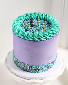 a purple and blue cake with sprinkles on it's bottom layer