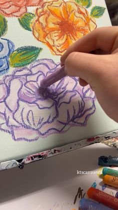 someone is drawing flowers on a canvas with crayons