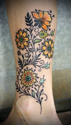 a woman's leg with flowers and leaves painted on the side by an artist