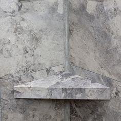 the corner of a shower with marble walls