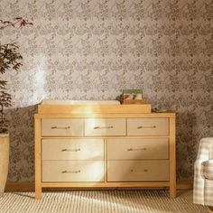 a living room with a dresser, chair and potted plant