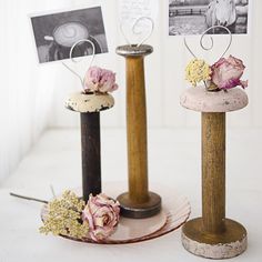 three wooden poles with flowers on them and pictures hanging from them, all in different shapes and sizes