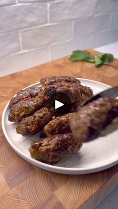 a person is cutting meat on a white plate