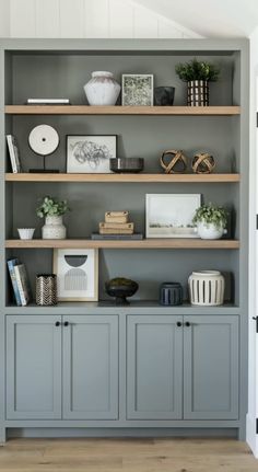 an open bookcase with books, vases and pictures on it