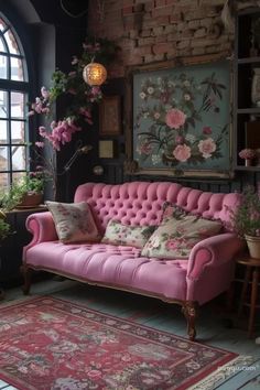 a pink couch sitting in front of a window next to a rug and potted plants