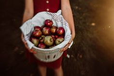 a woman holding a basket full of apples