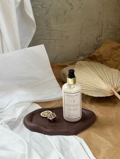 a bottle of lotion sitting on top of a brown plate next to an umbrella