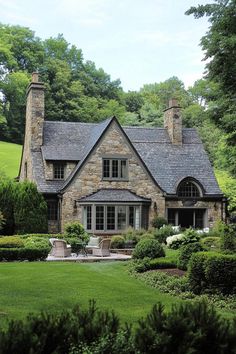 a stone house in the middle of a lush green field with trees and bushes around it