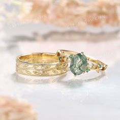 two wedding rings, one with an oval green stone and the other with diamond accents