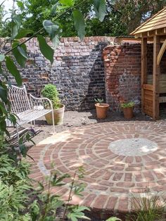 a brick patio with a bench and potted plants in the corner next to it