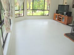 an empty living room with white floors and windows