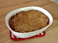 a casserole dish filled with oatmeal crumbs on top of a wooden table