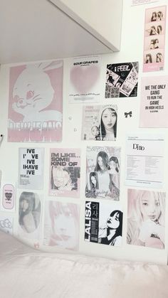 a wall covered in posters and stickers next to a bed with sheets on it