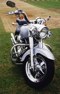 a silver motorcycle parked on top of a lush green field next to a soccer field