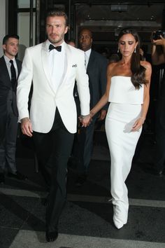 a man and woman dressed in white walking together