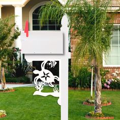 a white sign sitting on the side of a lush green field next to a palm tree