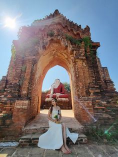 a woman sitting on the ground in front of an archway