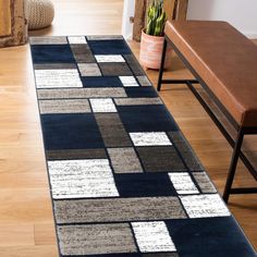 a blue and gray rug sitting on top of a wooden floor next to a bench