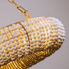 a chandelier with white beads hanging from it's sides and gold chains