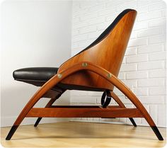 a wooden chair sitting on top of a hard wood floor next to a white brick wall