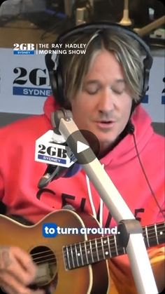 a man with headphones is playing an acoustic guitar in front of a microphone and recording equipment