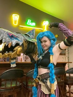 a woman with blue hair and braids standing in front of a bar wearing a costume