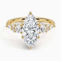 a yellow gold ring with a pear shaped diamond surrounded by small white diamonds on the band