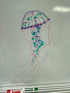 a drawing of a jellyfish on a whiteboard with marker markers in front of it