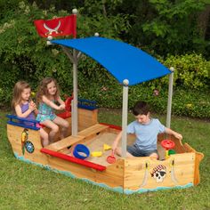 two children playing in a wooden pirate ship sandbox with blue canopy and red roof