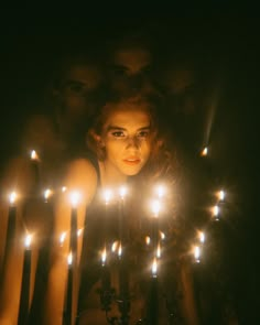 a woman is surrounded by candles in the dark