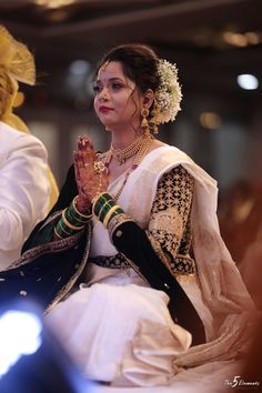 a woman sitting down with her hands clasped to her chest while wearing a white and green outfit