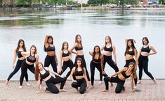 a group of women standing next to each other in front of a body of water